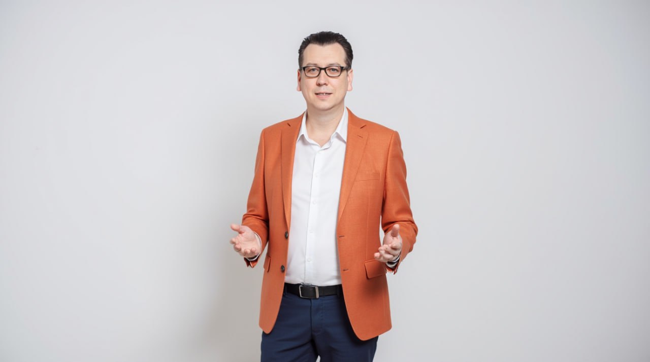 Заказать современный и функциональный сайт — обращайтесь в SeoVolga Артем Чусов - генеральный директор в оранжевом пиджаке улыбается и приветственно разводит руки.